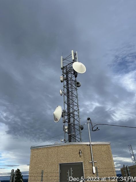 A telephone tower with satellite dishes on top of a building.