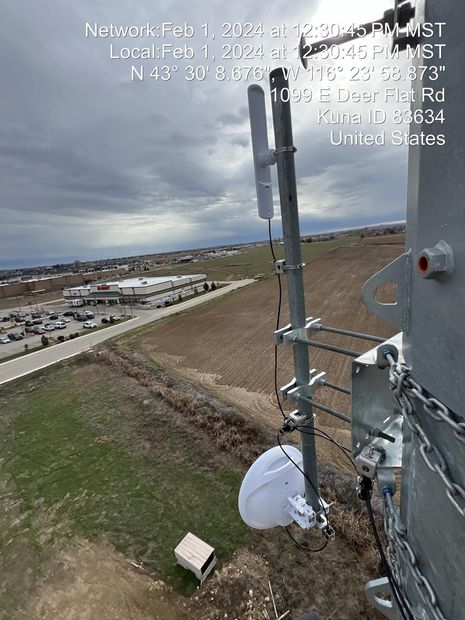 A satellite dish is attached to a pole in a field.