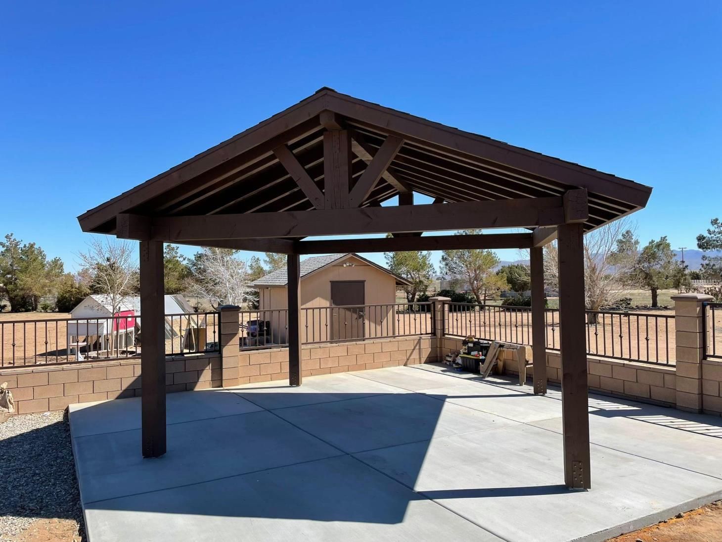 A wooden pavilion with a concrete floor and a blue sky in the background