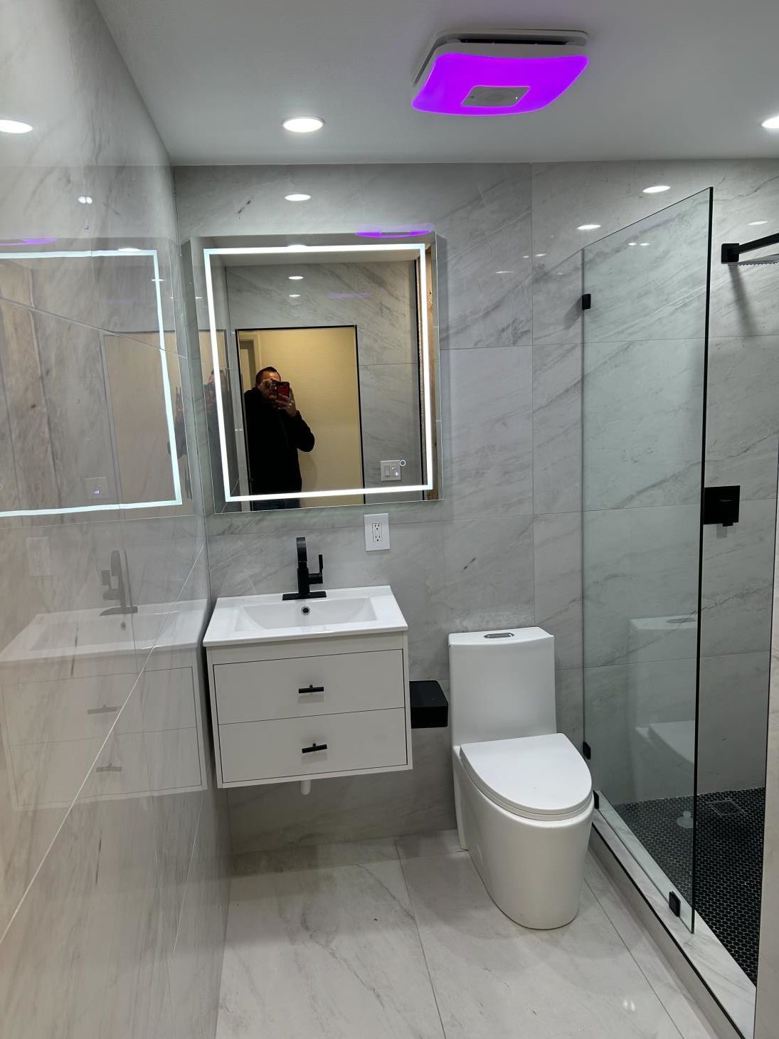 A plumber is fixing a shower head in a bathroom.