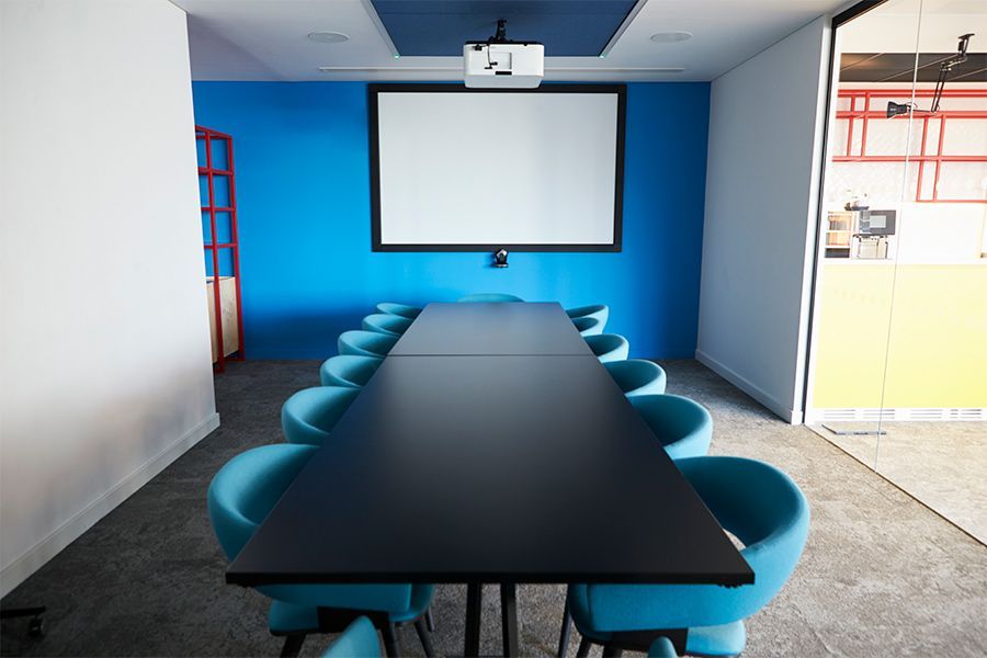 A conference room with a long table and chairs and a projector screen.