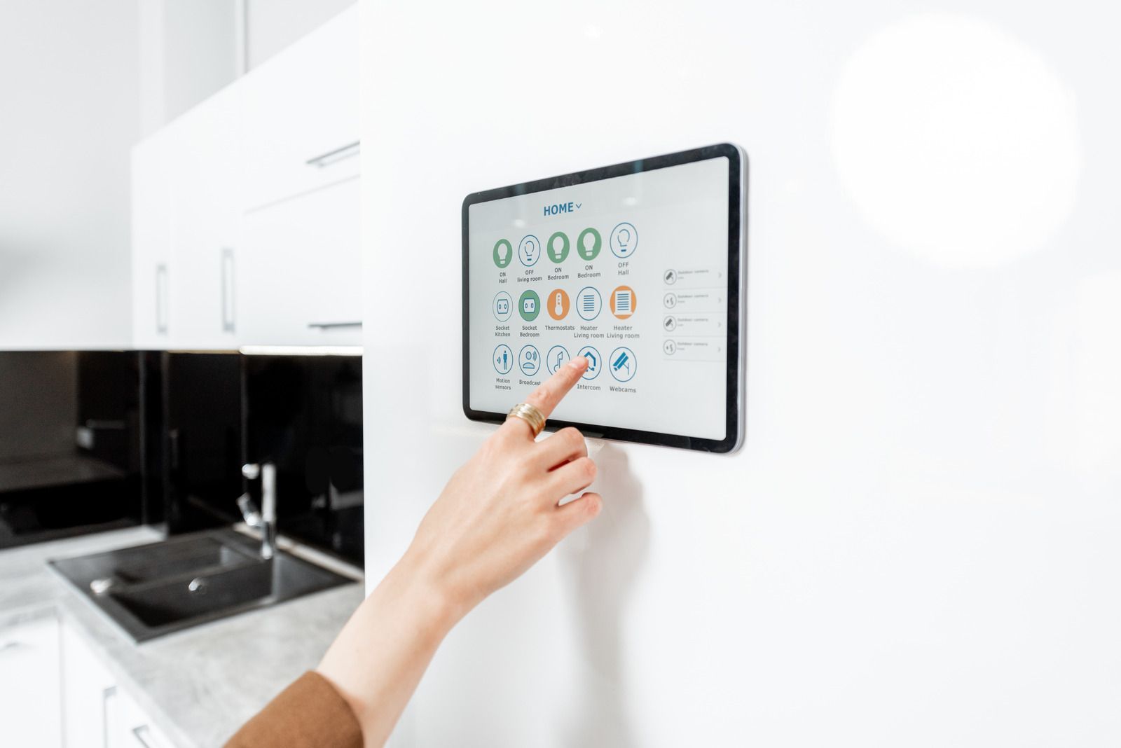 A person is pressing a button on a tablet in a kitchen.