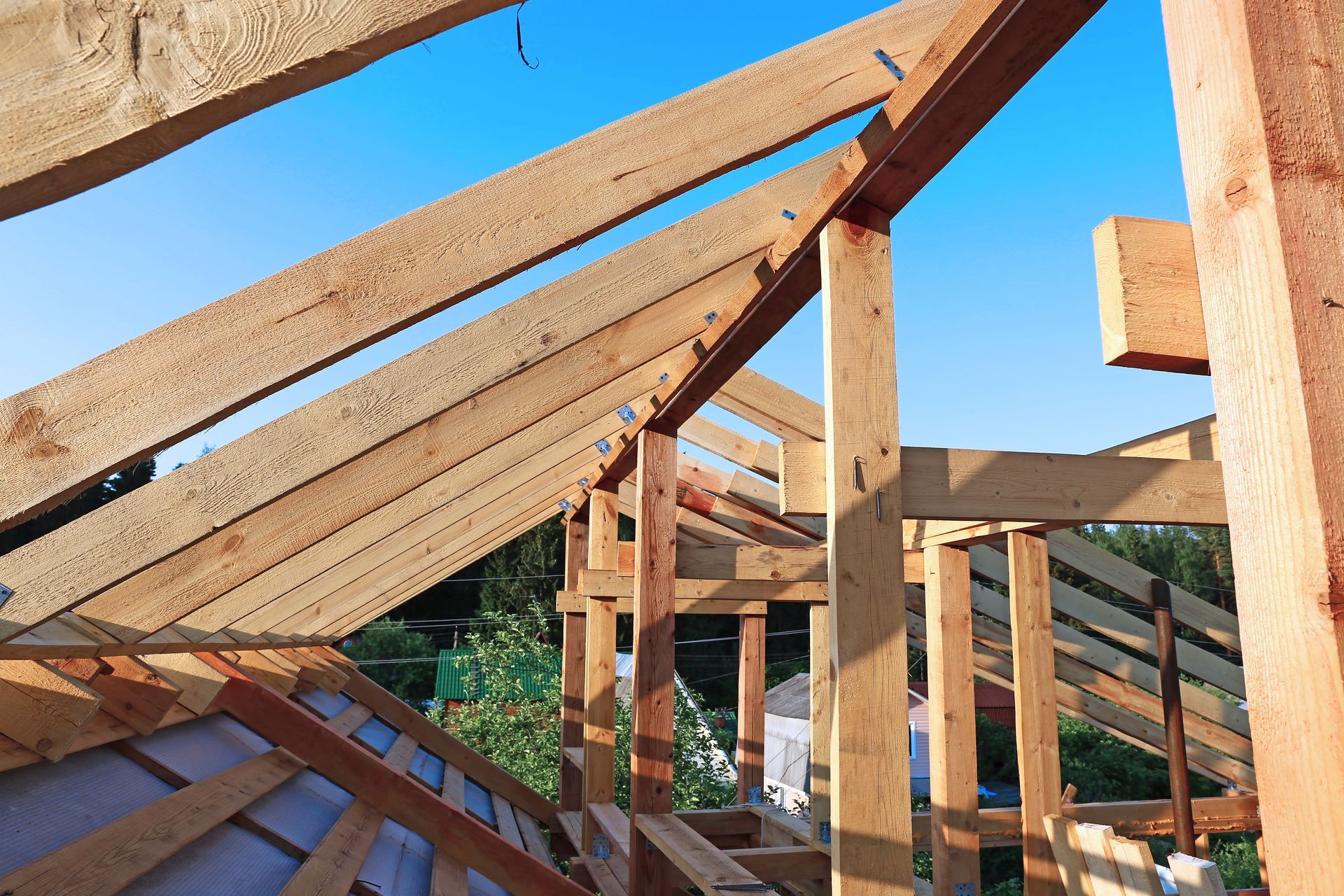 Une structure en bois est en cours de construction avec un ciel bleu en arrière-plan.
