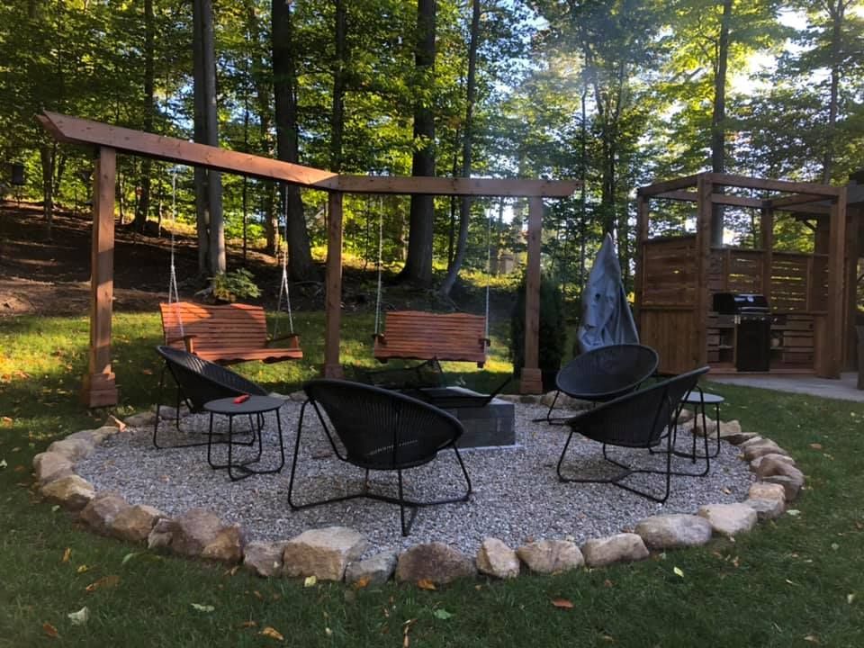 Il y a un foyer au milieu de la cour avec des chaises et une balançoire.