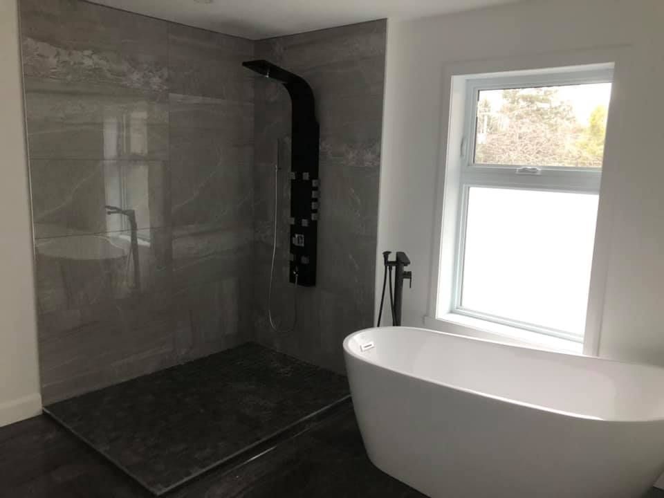 Une salle de bain avec baignoire, douche et fenêtre.