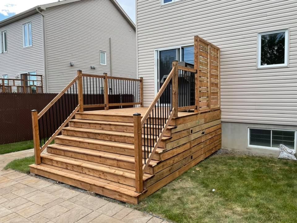 Une terrasse en bois avec des escaliers qui y mènent se trouve dans l'arrière-cour d'une maison.