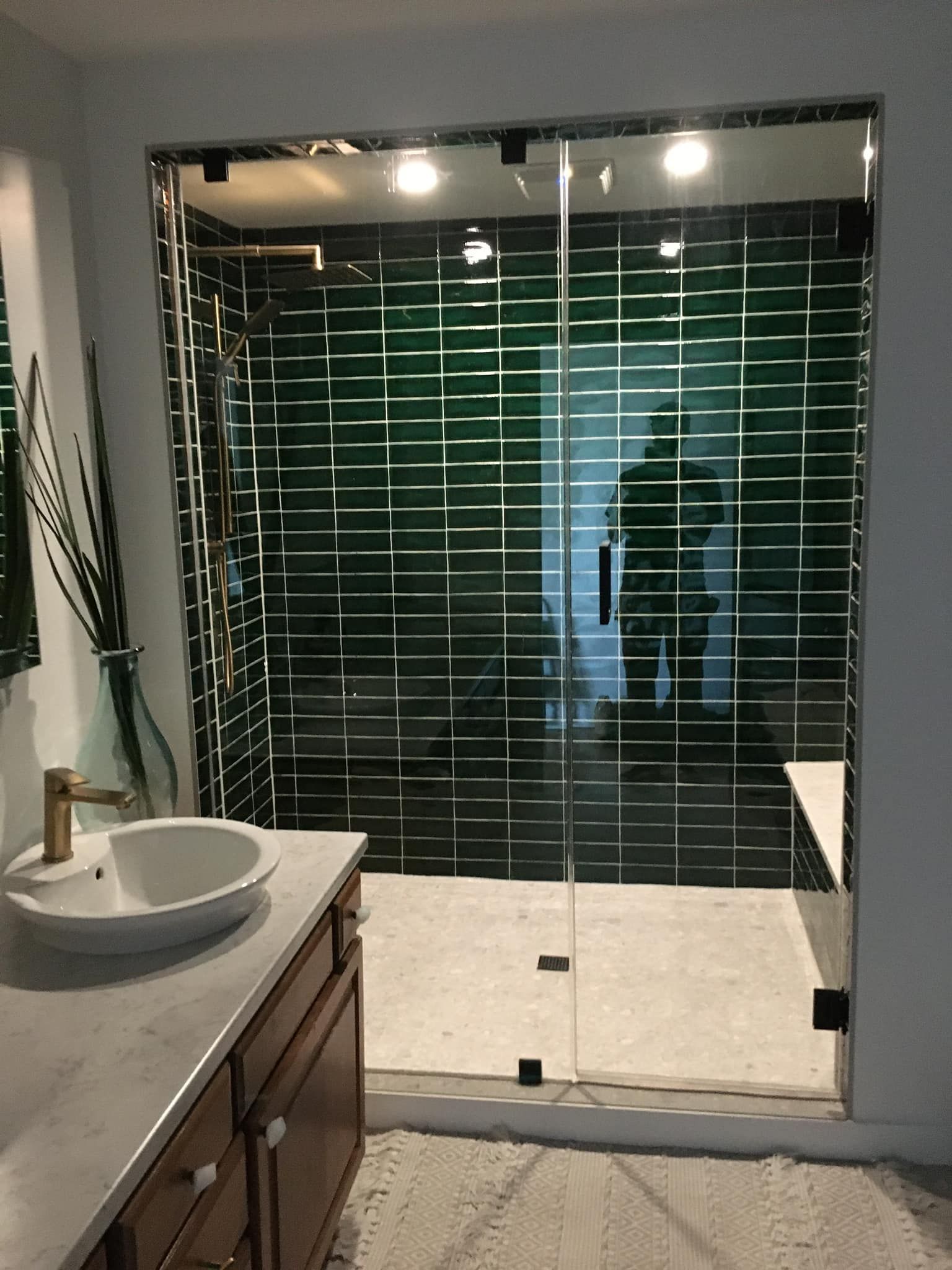Une salle de bain avec un lavabo et une douche à l'italienne avec carrelage vert.