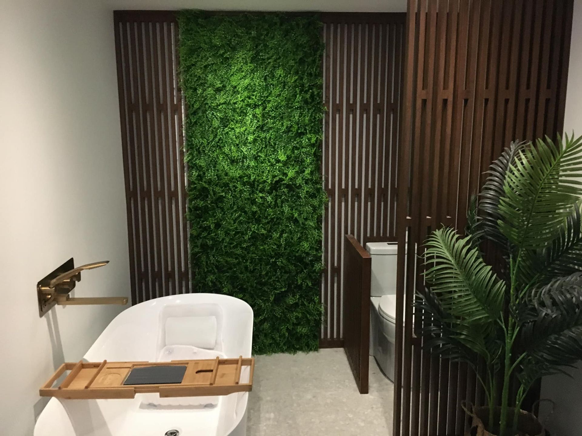 Une salle de bain avec baignoire, toilettes et mur végétalisé.
