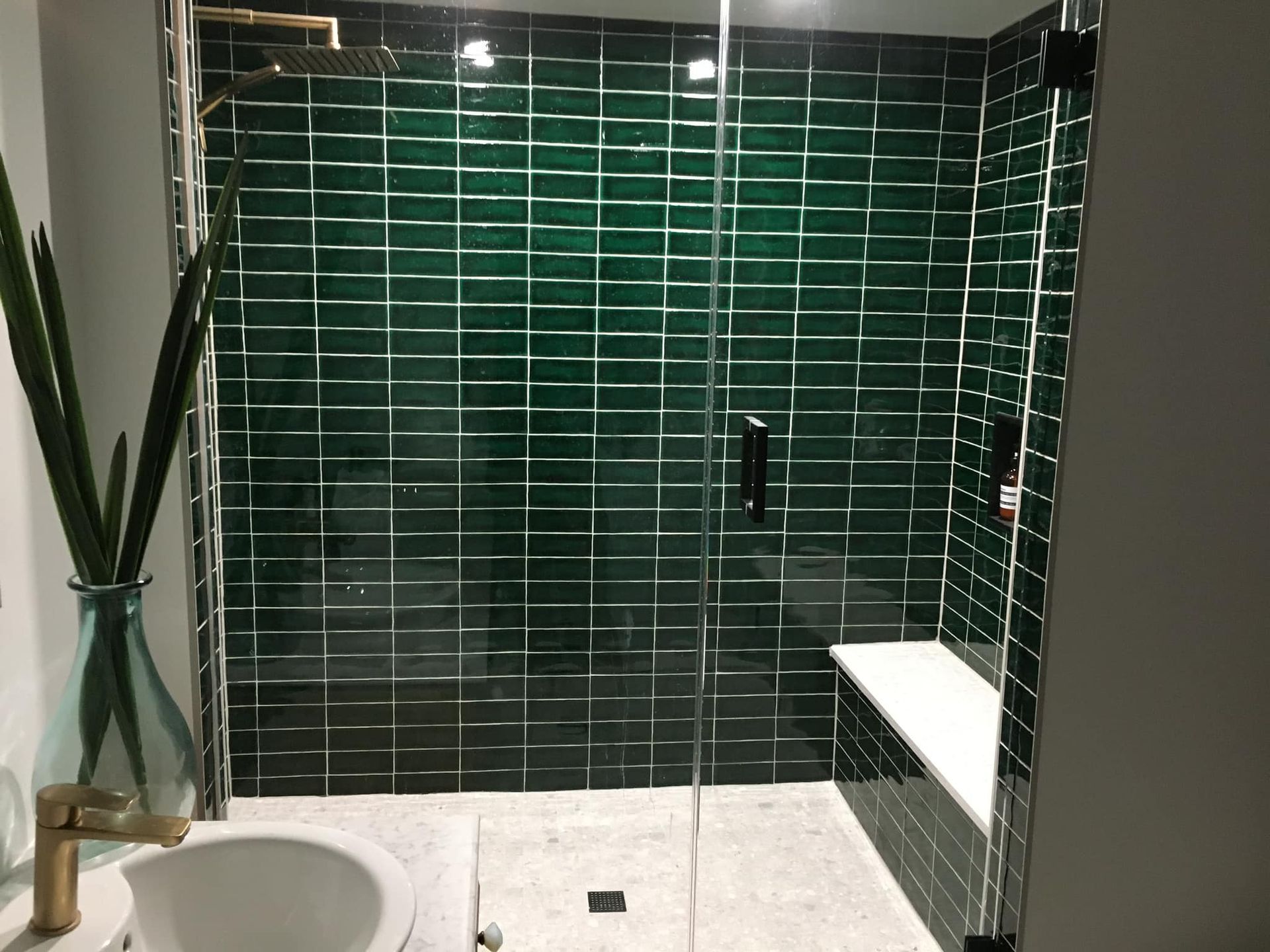 Une salle de bain avec carrelage vert, un lavabo et une douche à l'italienne.