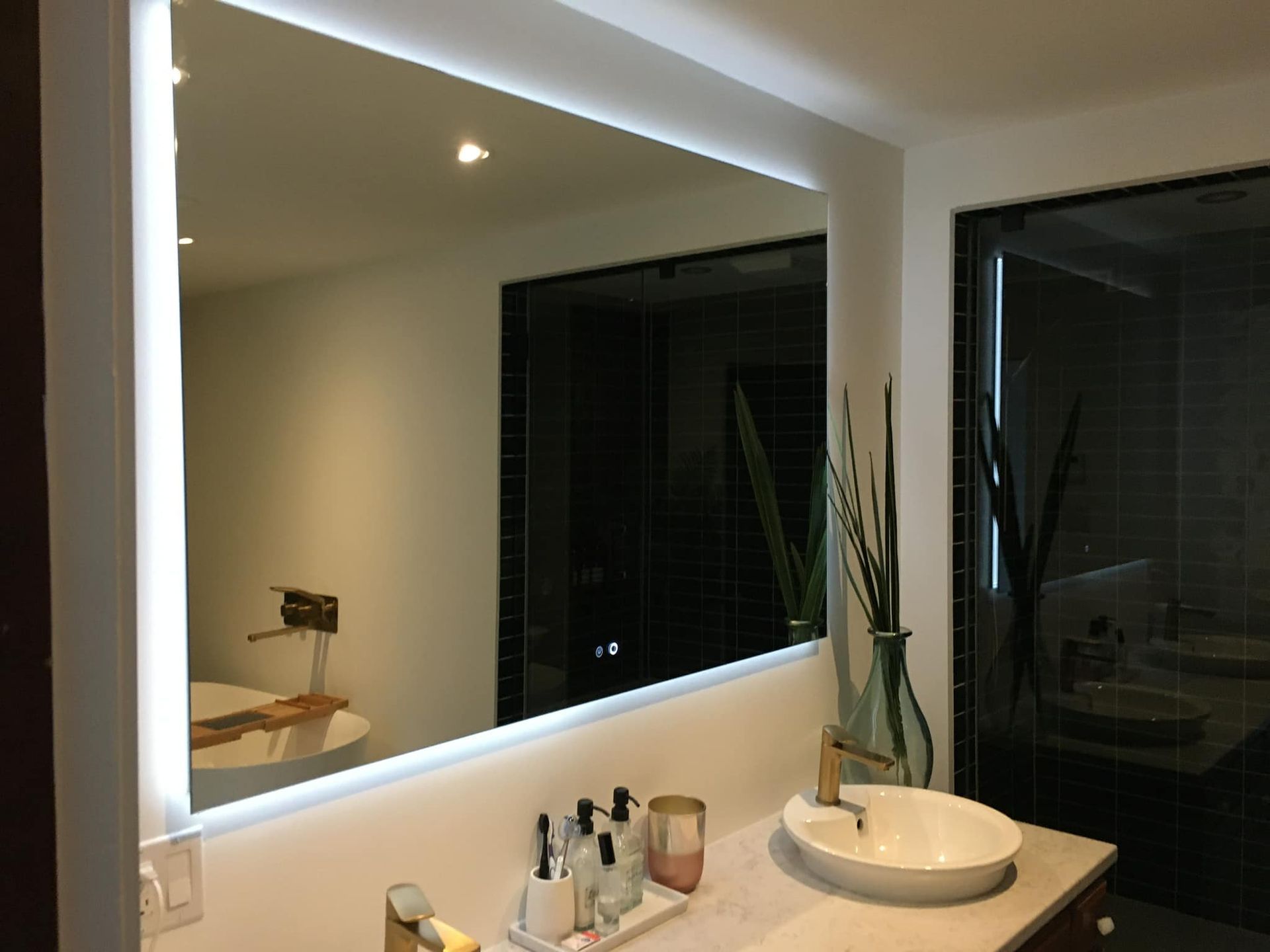 Une salle de bain avec un grand miroir et un lavabo.