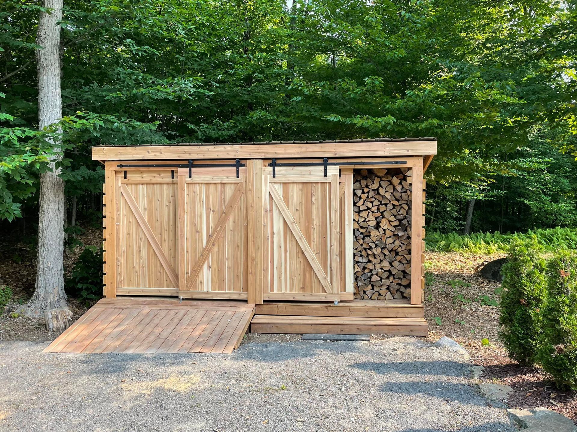 Un hangar en bois avec des portes coulissantes se trouve au milieu d'une forêt.