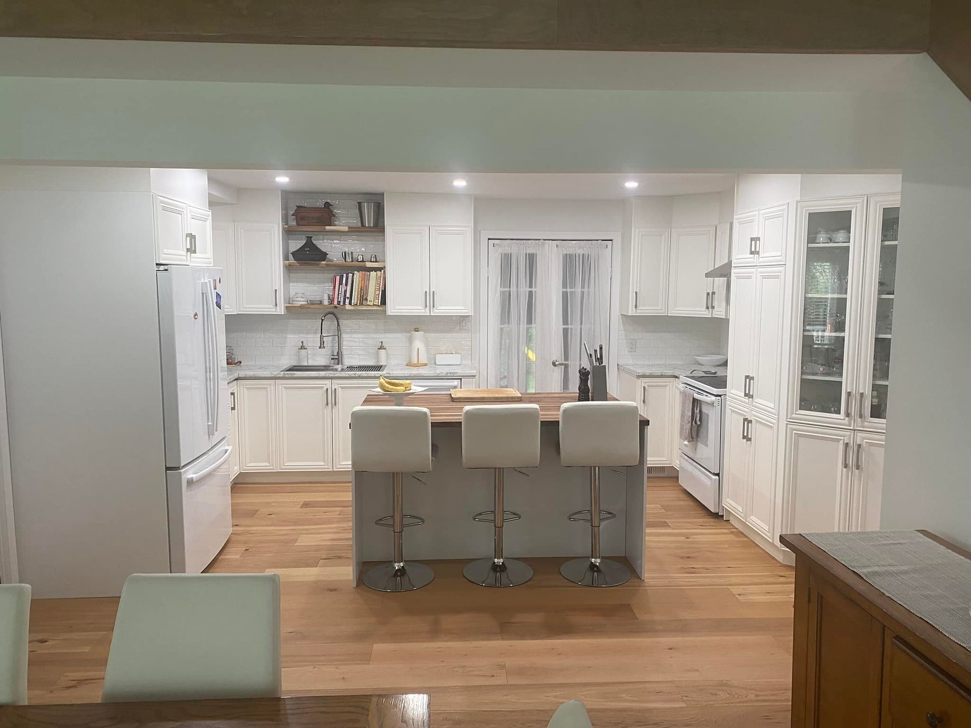 Une cuisine avec des armoires blanches et un grand îlot au milieu.