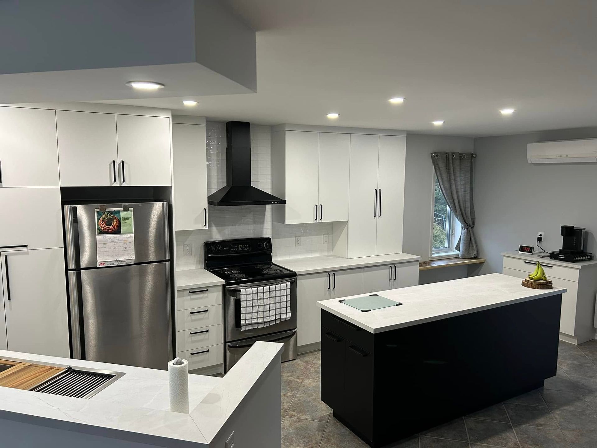 Une cuisine avec des appareils électroménagers en acier inoxydable, des armoires blanches et un grand îlot.