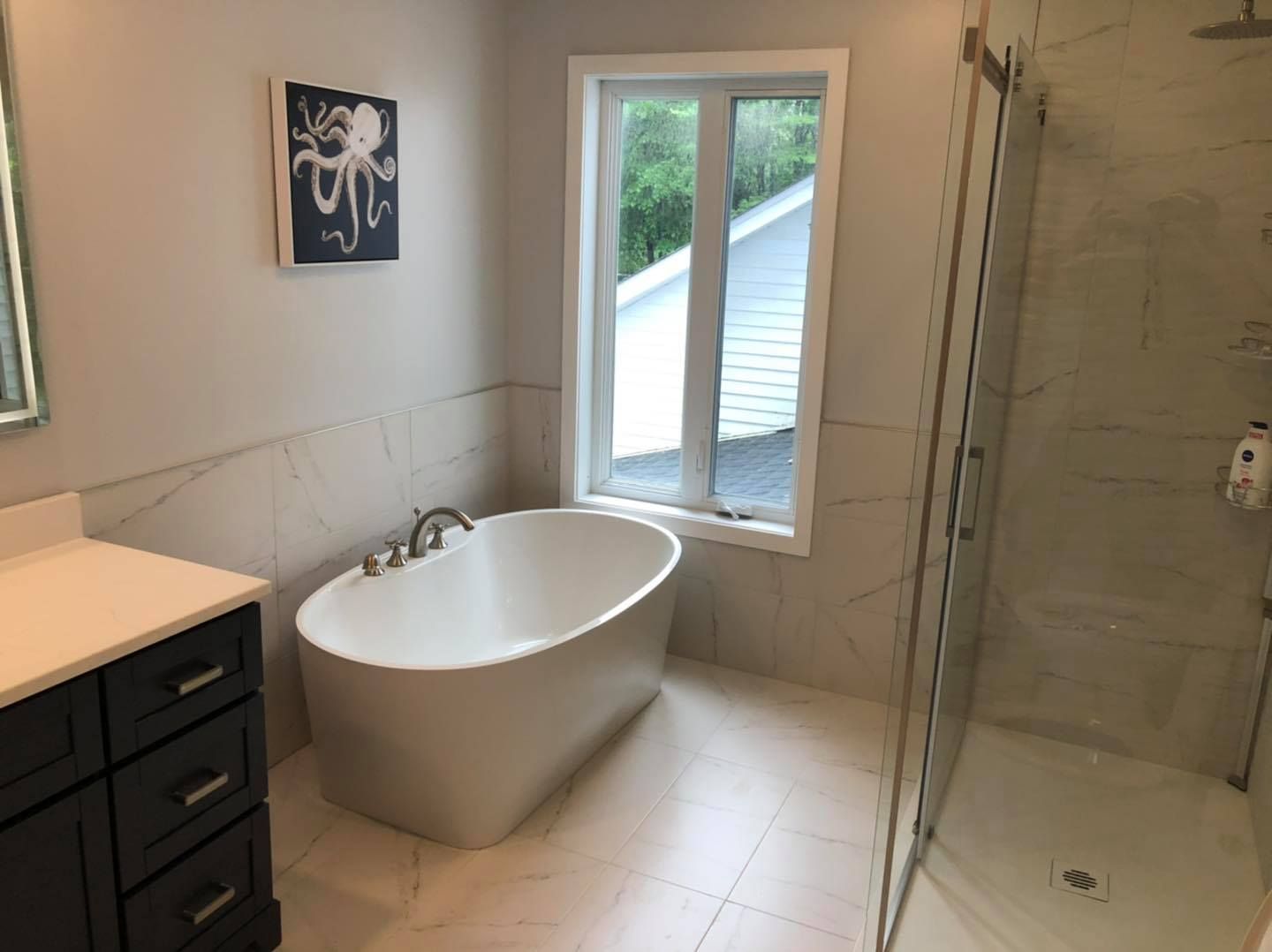 Une salle de bain avec baignoire, lavabo, douche et fenêtre.