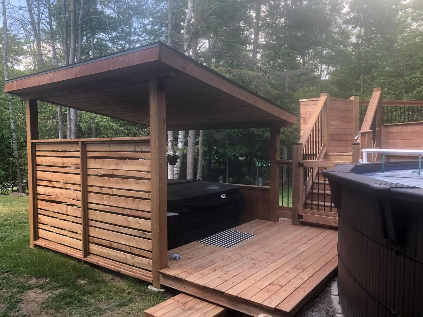 Un bain à remous est installé sous un belvédère en bois sur une terrasse.