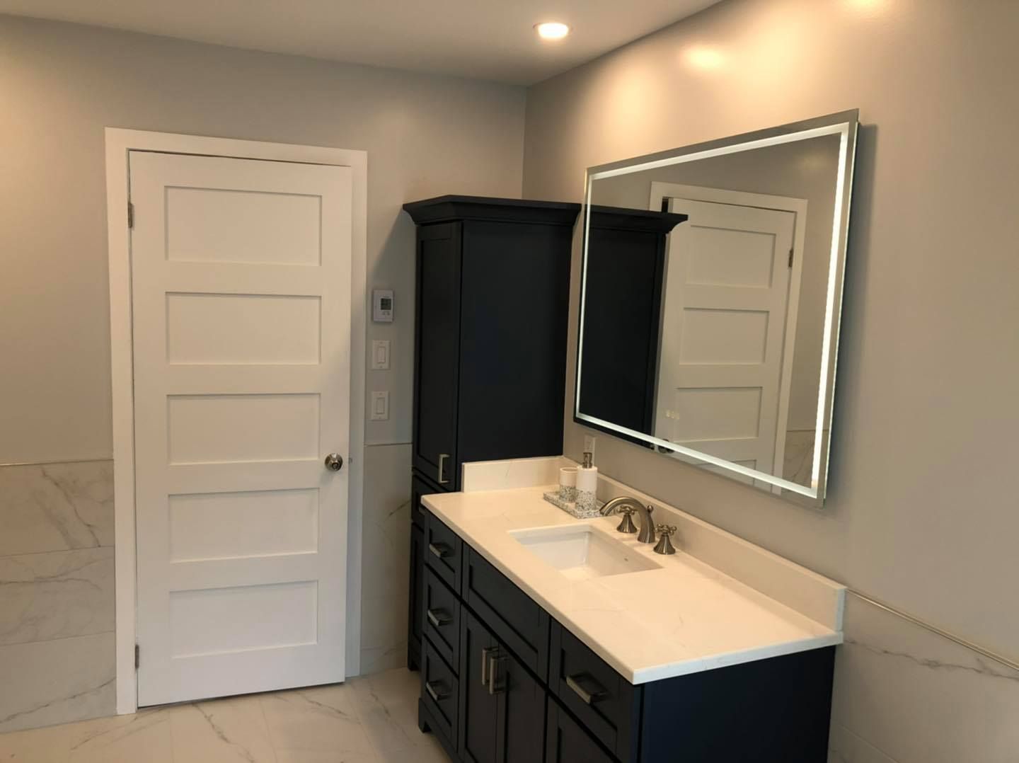 Une salle de bain avec lavabo, miroir et armoires.