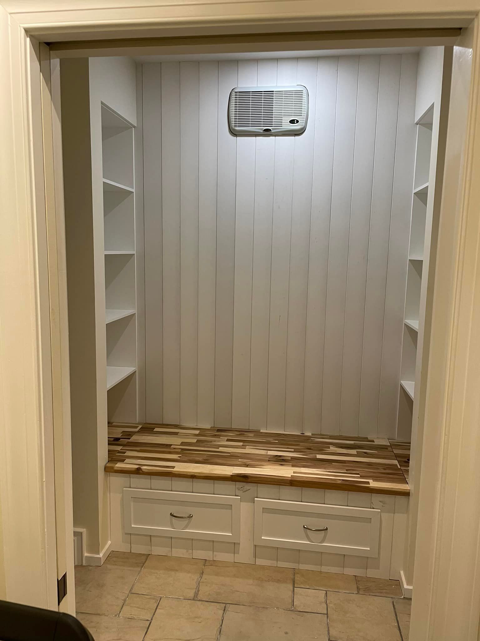 Un dressing avec un banc en bois et des étagères.