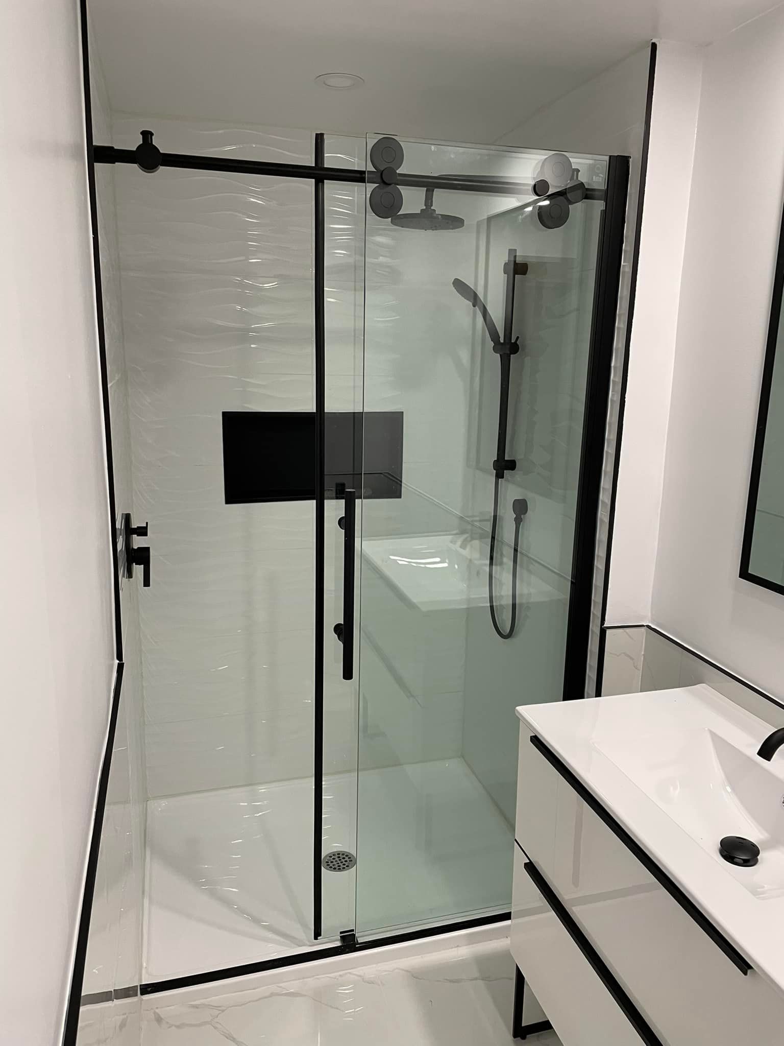 Une salle de bain avec une porte de douche coulissante en verre et un lavabo.