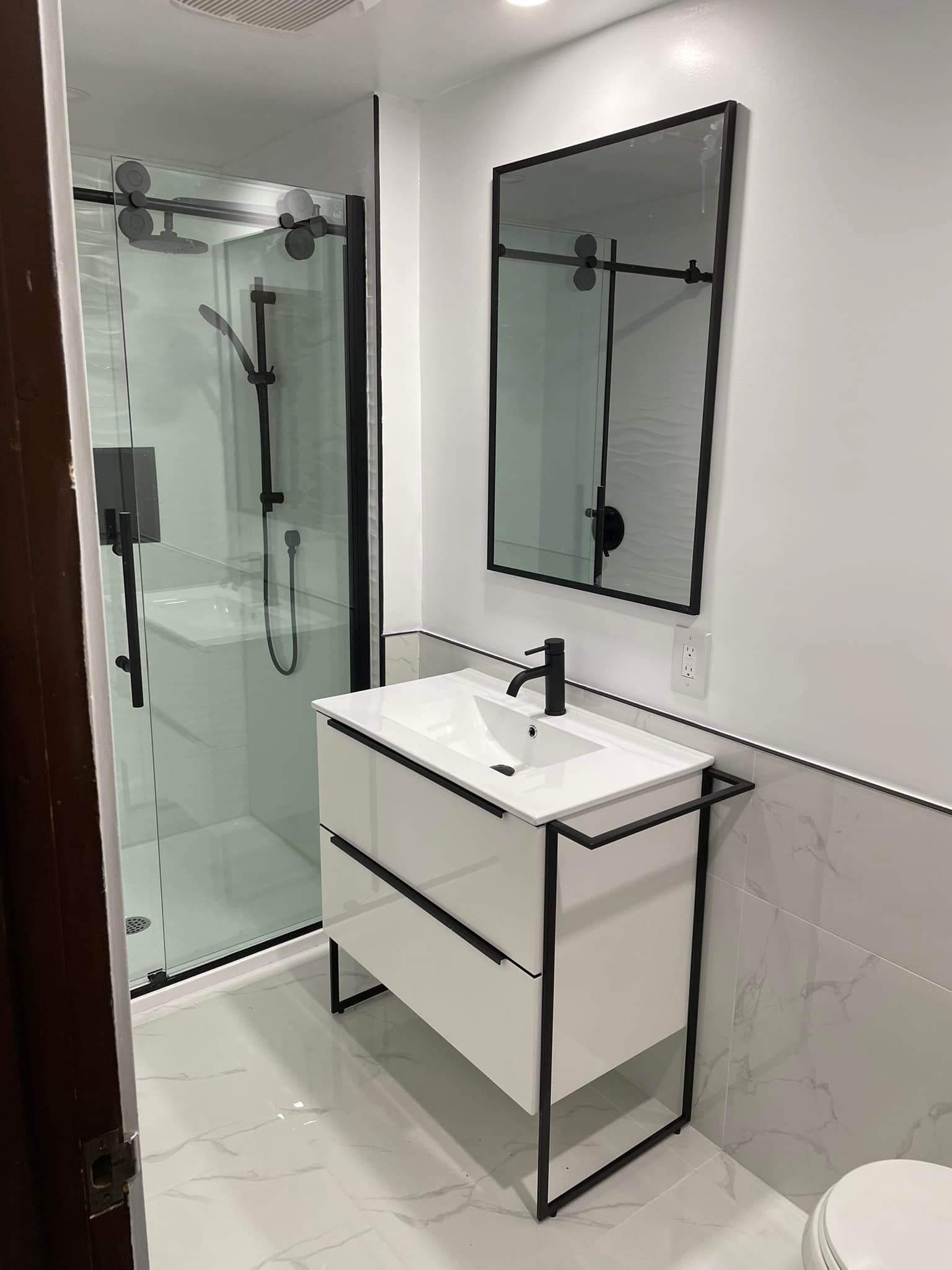 Une salle de bain avec lavabo, miroir, douche et WC.