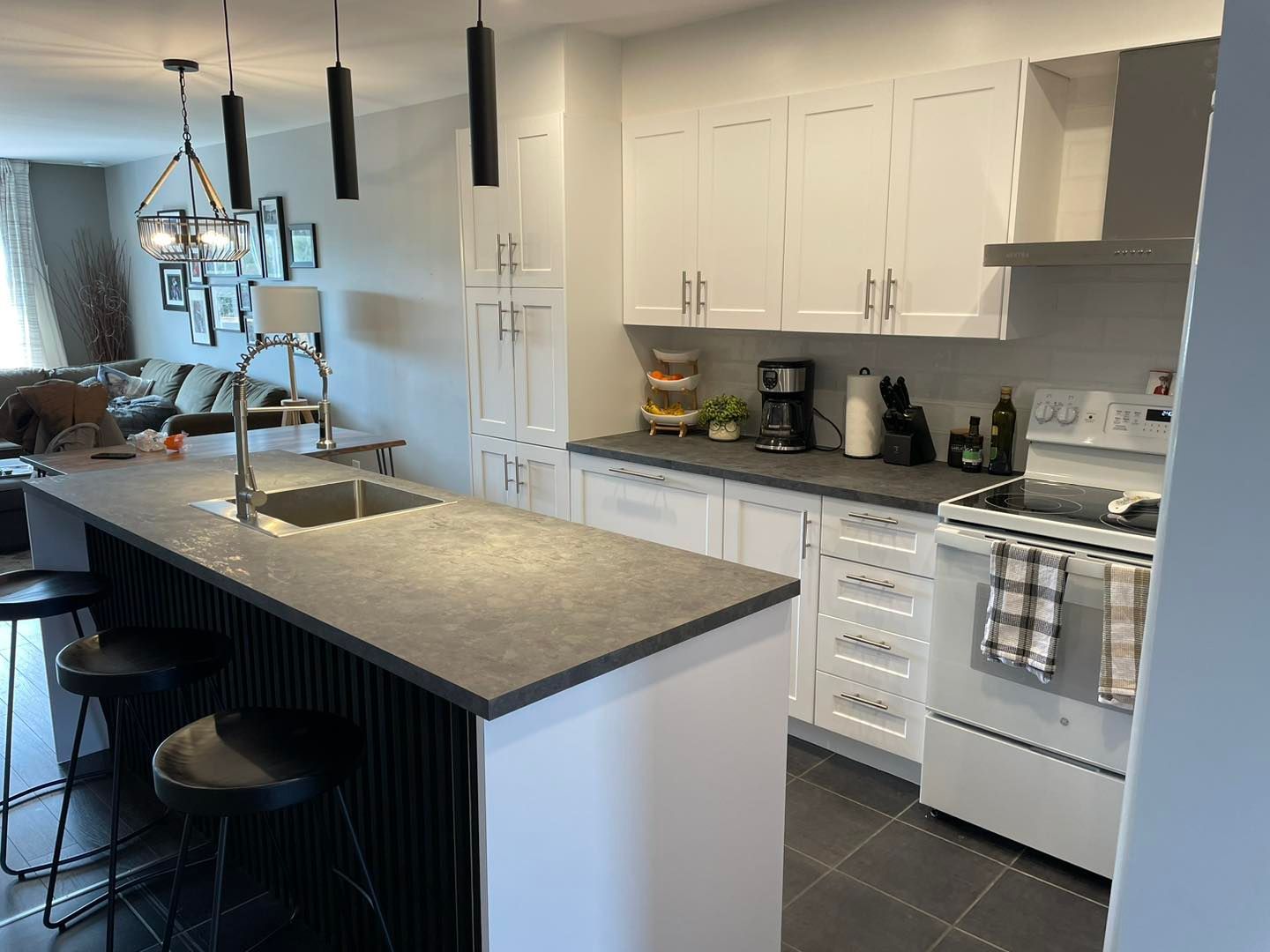 Une cuisine avec des armoires blanches, une cuisinière, un évier et un grand îlot.