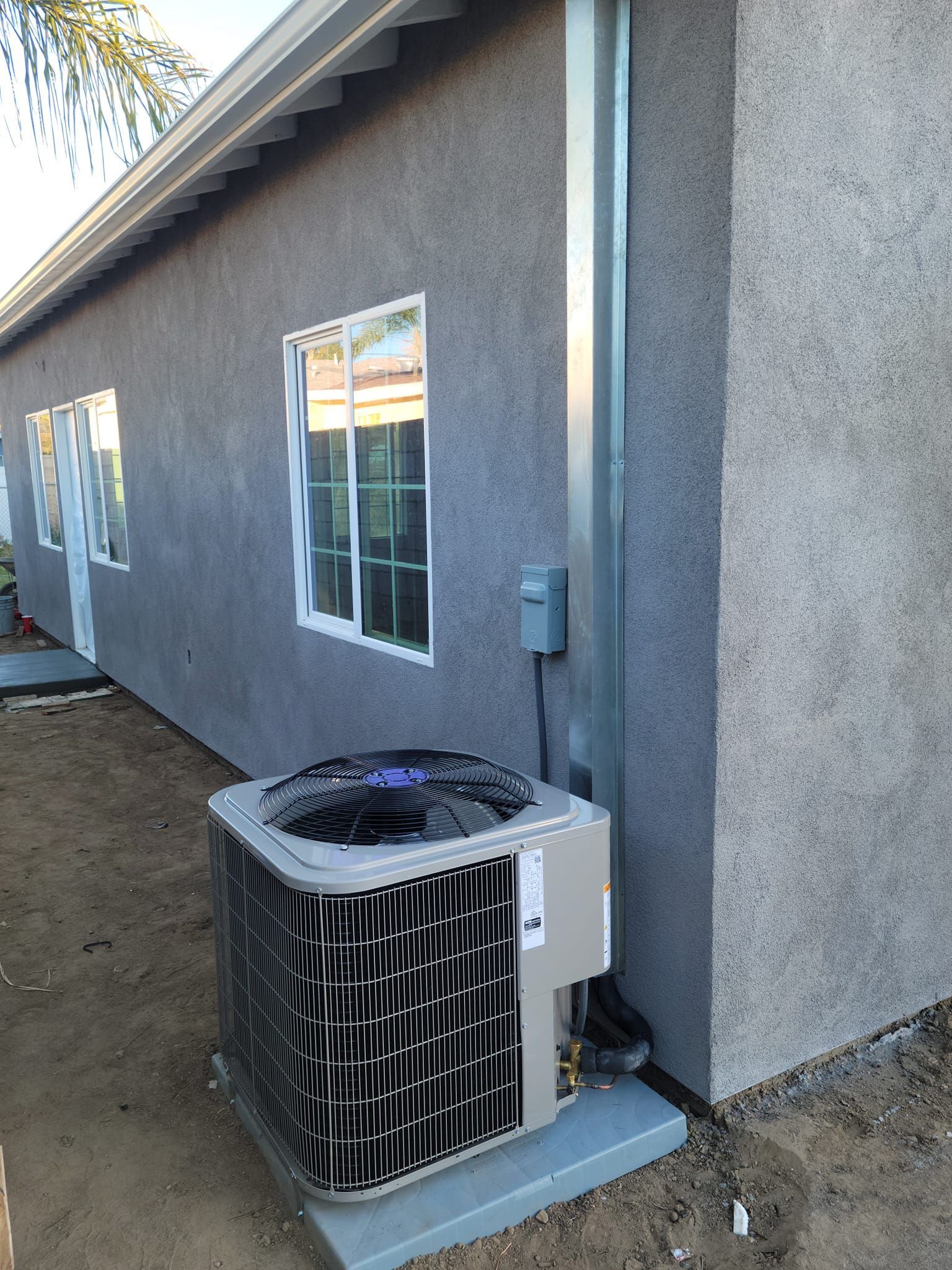 An air conditioner is sitting on the side of a house.