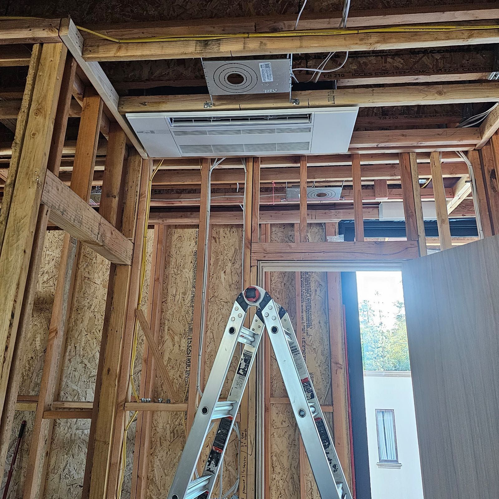 A ladder is sitting in the middle of a room in a house under construction.