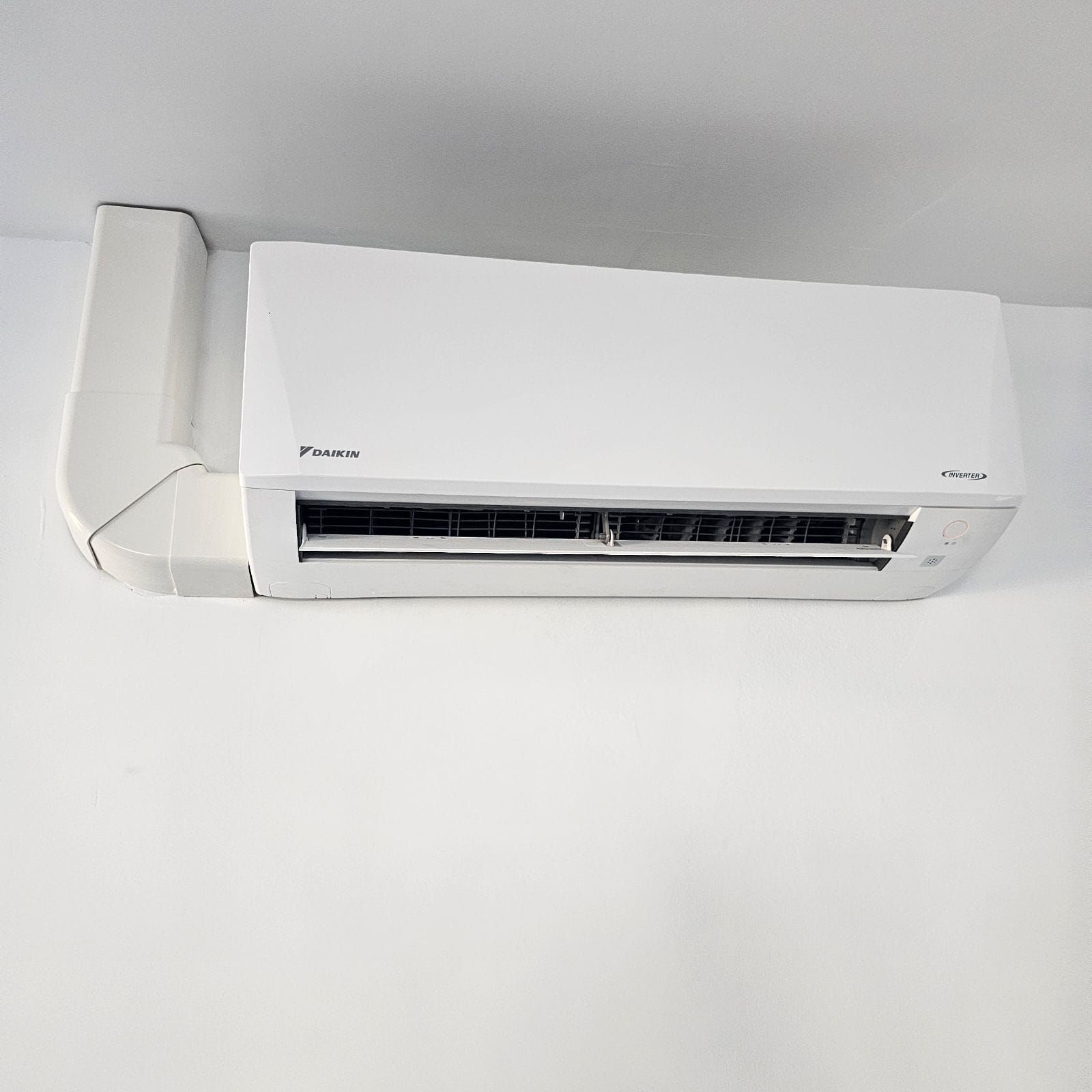 A white air conditioner is mounted on a white wall.
