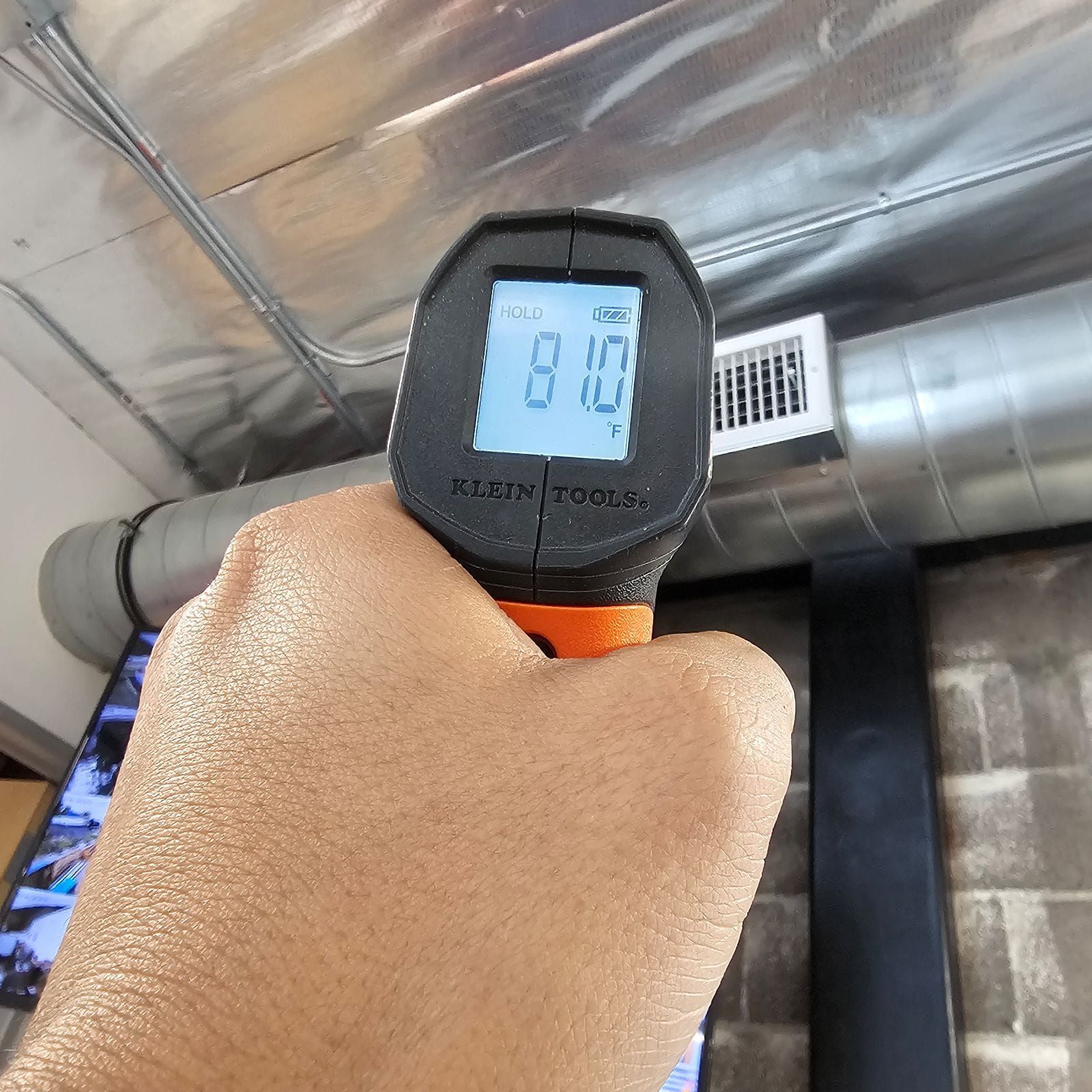 A hand is holding a digital thermometer that reads 8.15