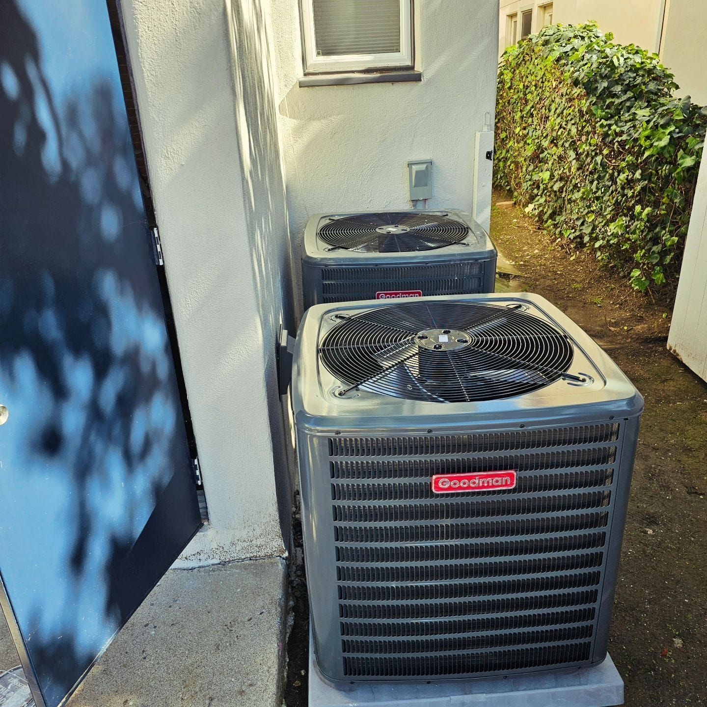 Two air conditioners are sitting outside of a building.