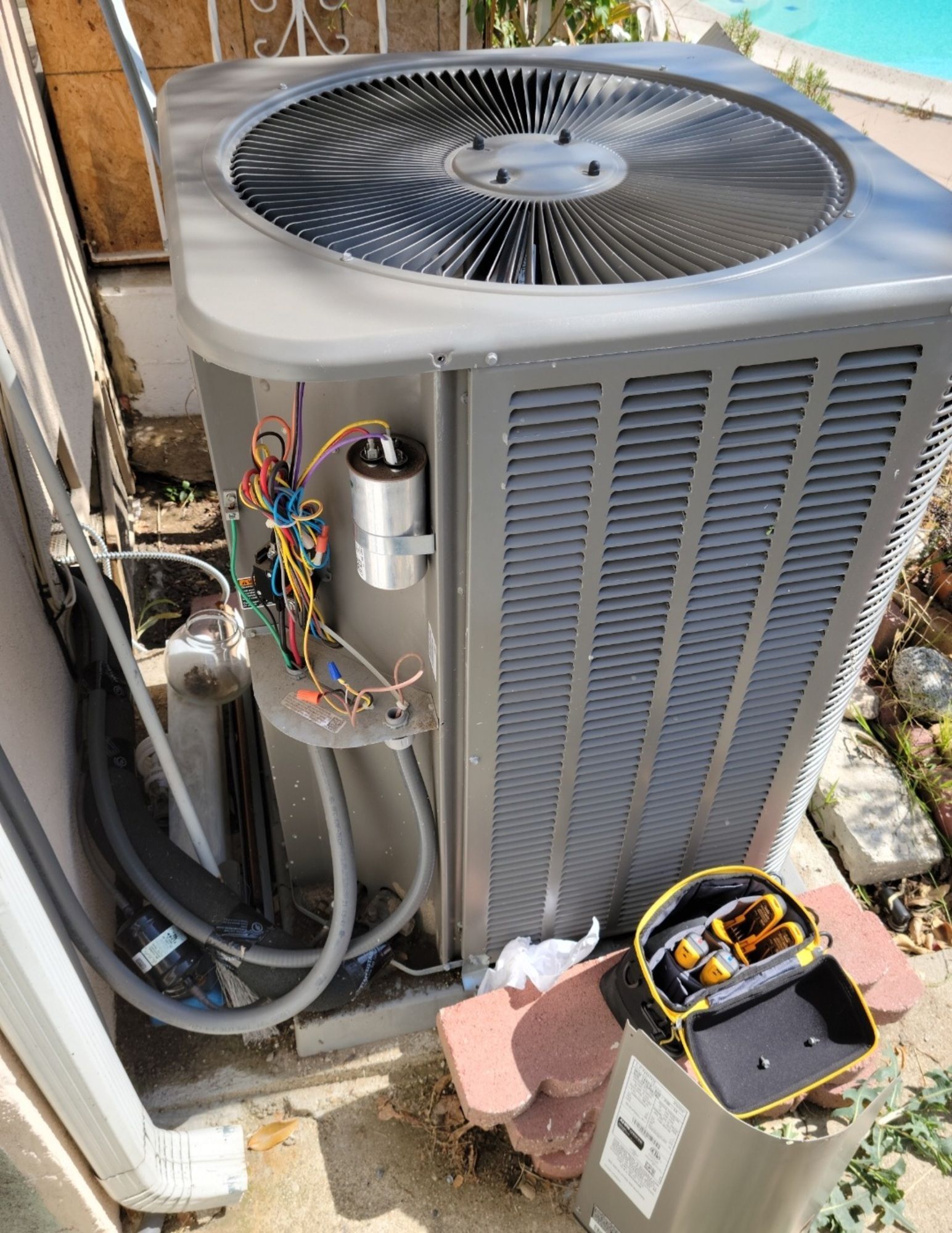 A large air conditioner is sitting on the side of a building next to a pool.