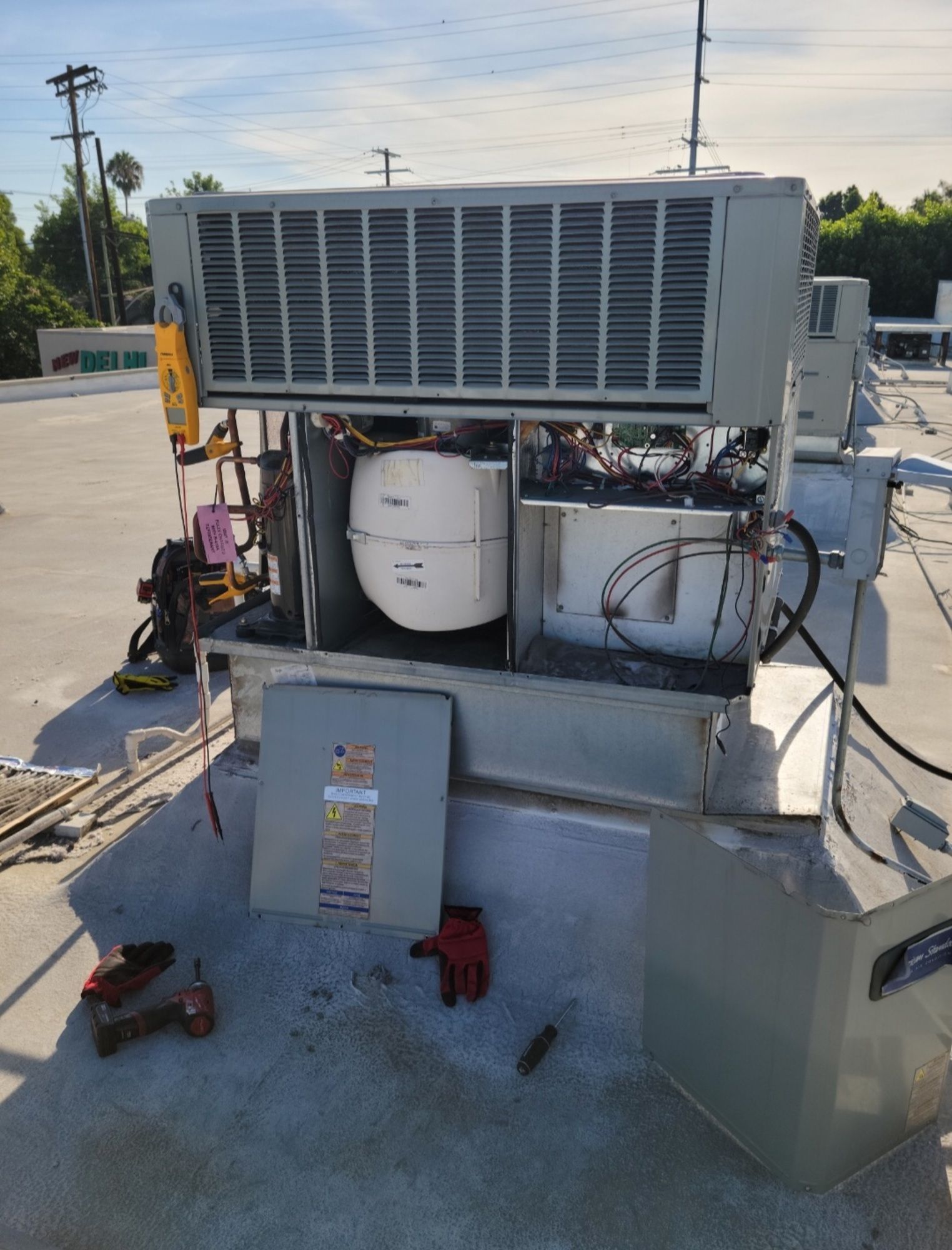 A large air conditioner is being repaired on the roof of a building.