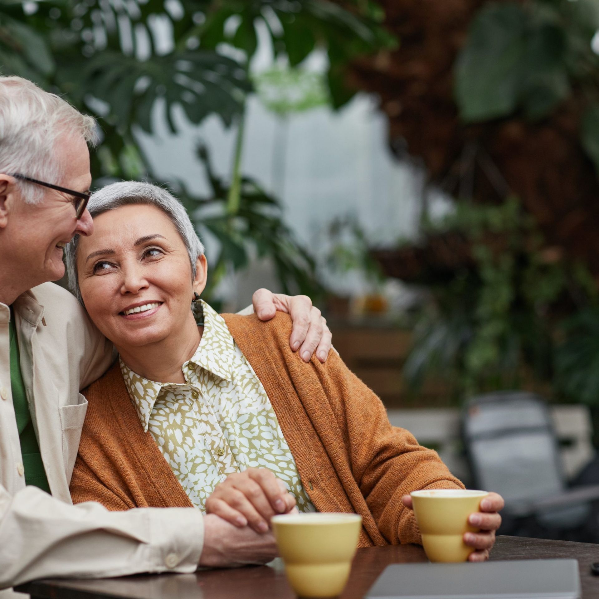 A man and a woman are sitting at a table with cups of coffee.