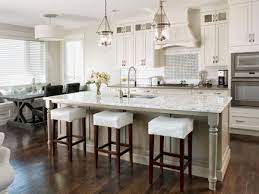 A kitchen with white cabinets and a large island with stools.