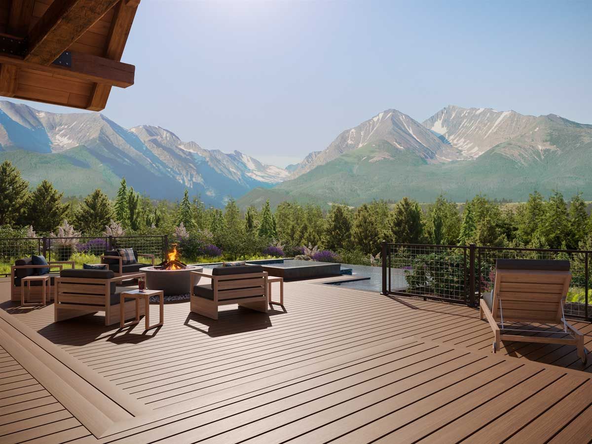 Trex® Decking from Budget Home Supply Colorado - Wooden deck with fire pit and seating, overlooking mountains and trees under a sunny sky.