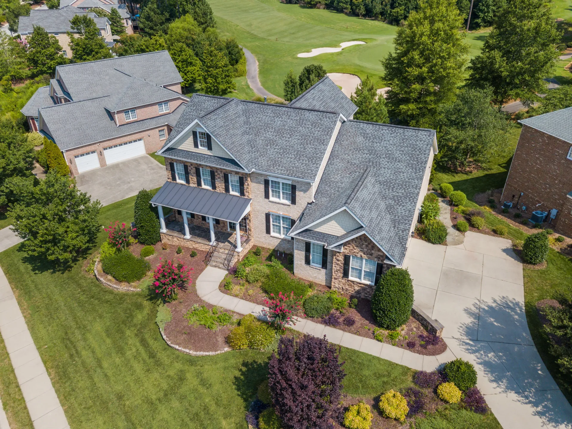 An aerial view of a large house with a golf course in the background.