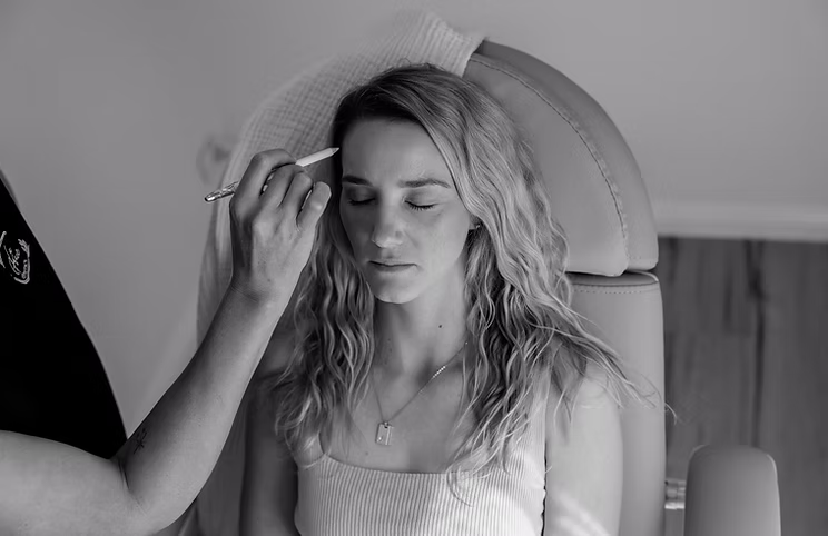A woman is getting her makeup done in a black and white photo.