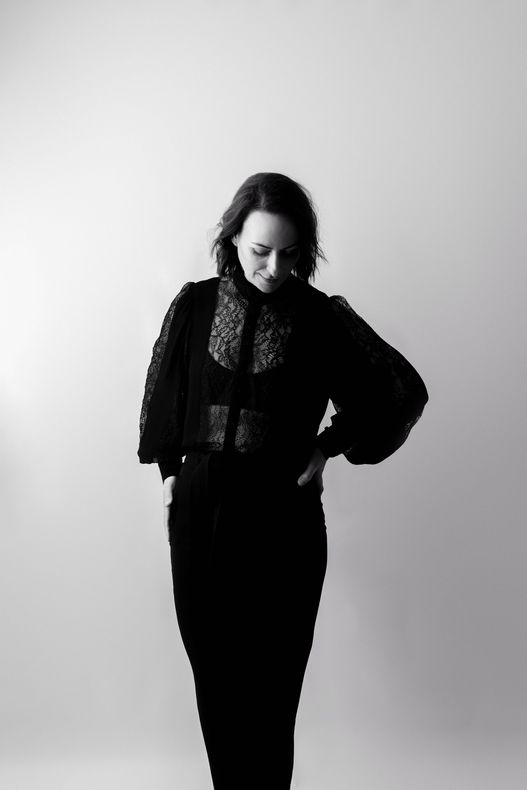 A black and white photo of a woman standing with her hands on her hips.
