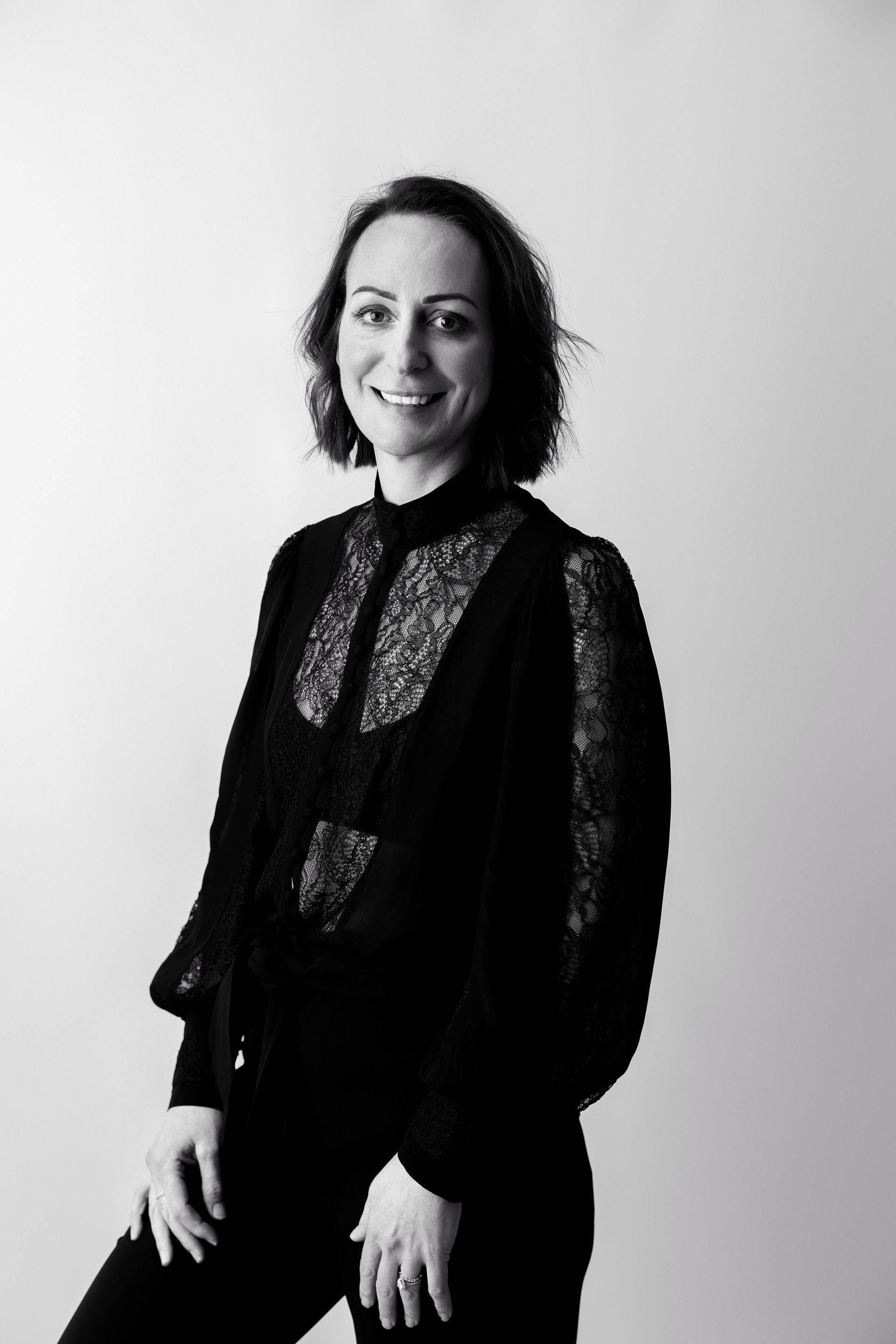 A black and white photo of a woman standing in front of a white wall.