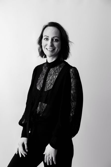 A black and white photo of a woman standing in front of a white wall.