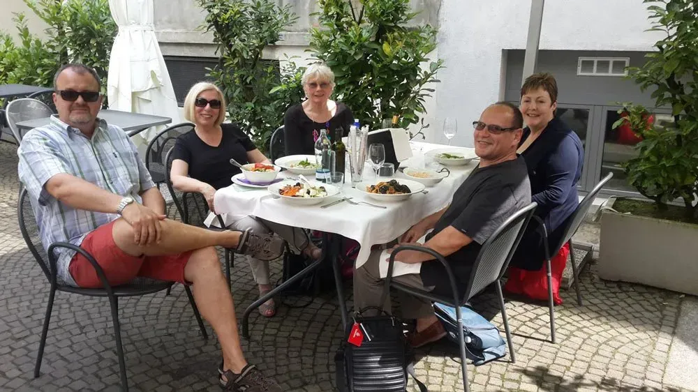 Relaxed lunch al fresco with wine, fresh pasta, and good company on a leafy patio.