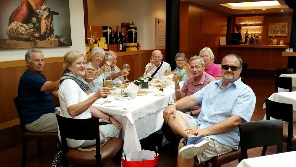 Group of people sitting around a restaurant table raising glasses in a toast.