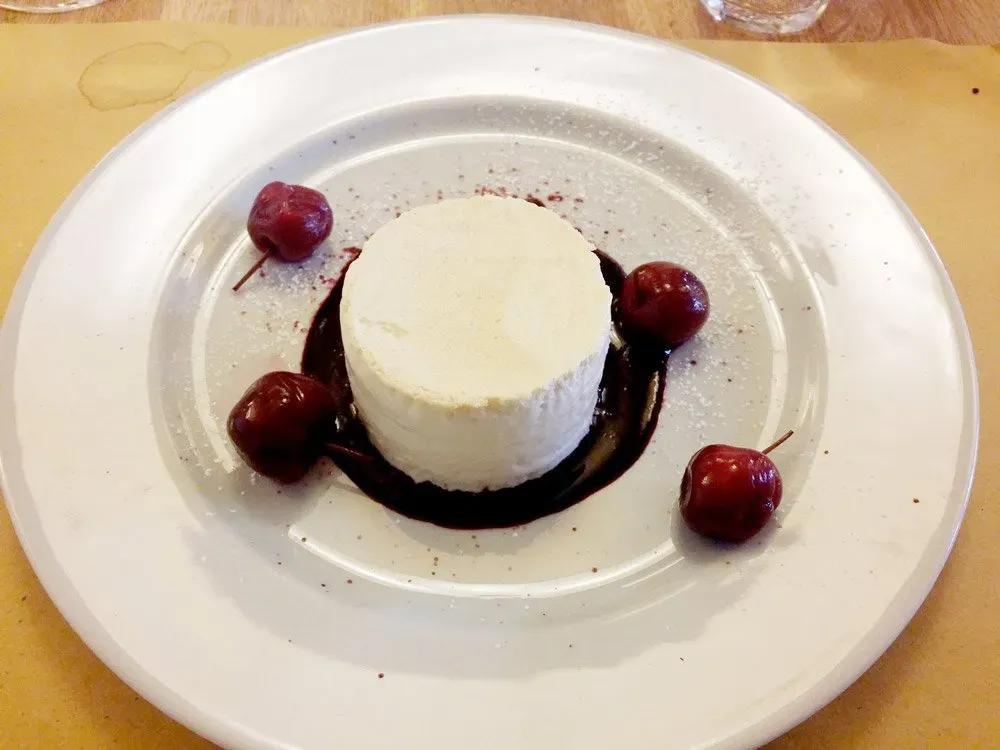 A plated dessert of semifreddo with cherries and berry sauce.