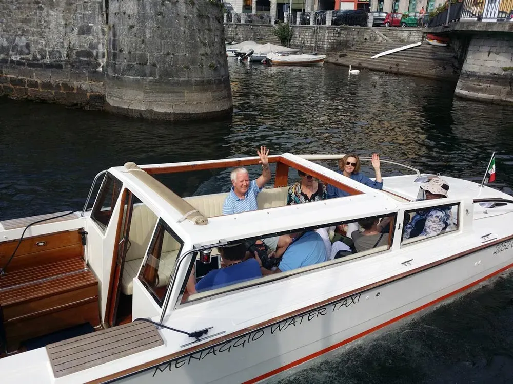 Group of people riding a Menaggio water taxi on a scenic Italian lake.