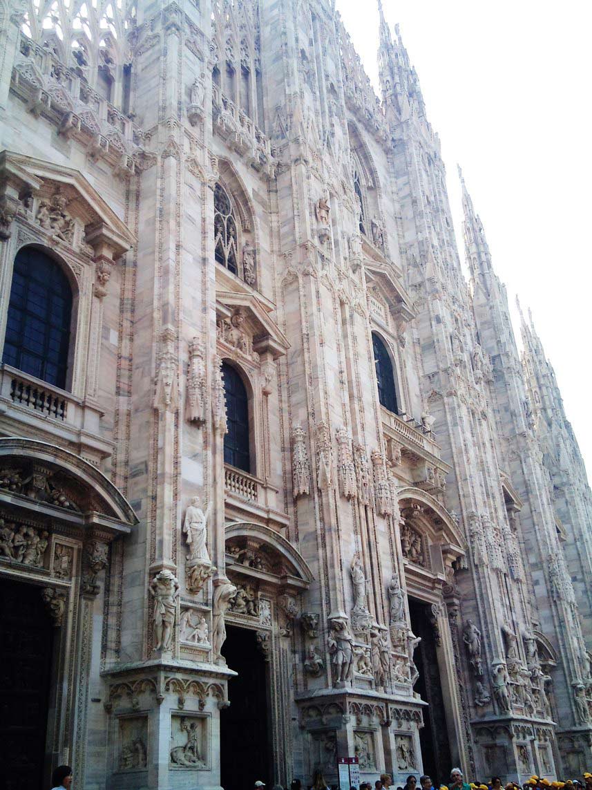 Close-up of Milan Cathedral’s intricate Gothic facade with arched windows, spires, and sculpted statues.