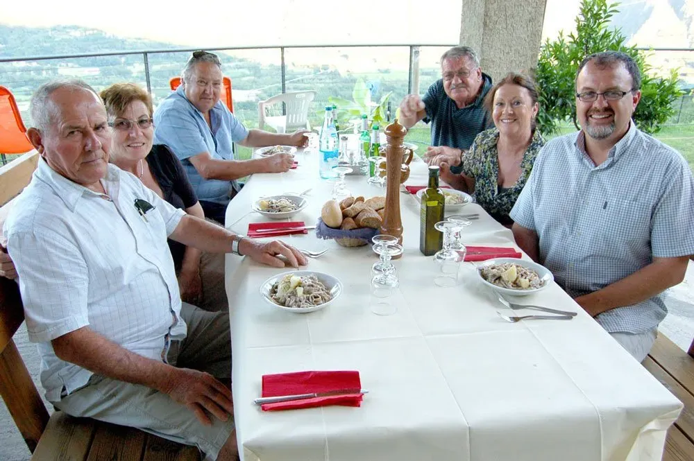 Outdoor pasta lunch with wine and views, shared among friends in a relaxed countryside setting.