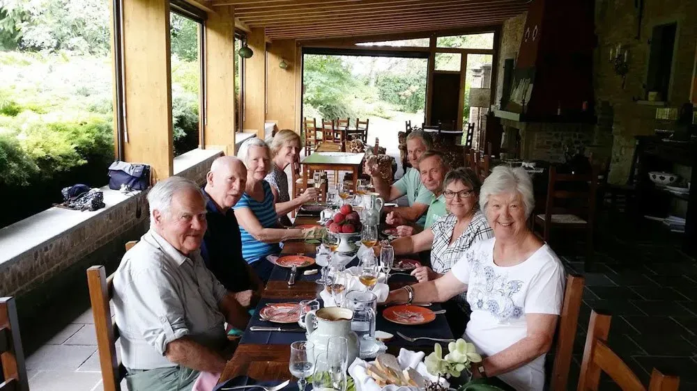 Group of people dining together at a long wooden table in a rustic open-air restaurant.