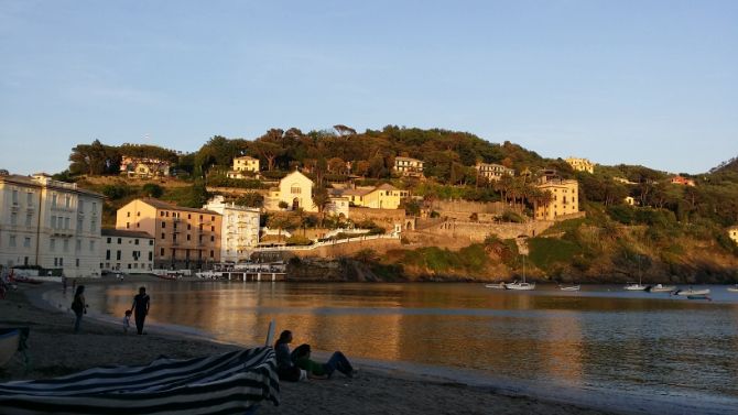 A group of people are sitting on a beach next to a body of water.