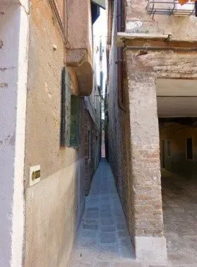 Extremely narrow alleyway between old brick buildings.