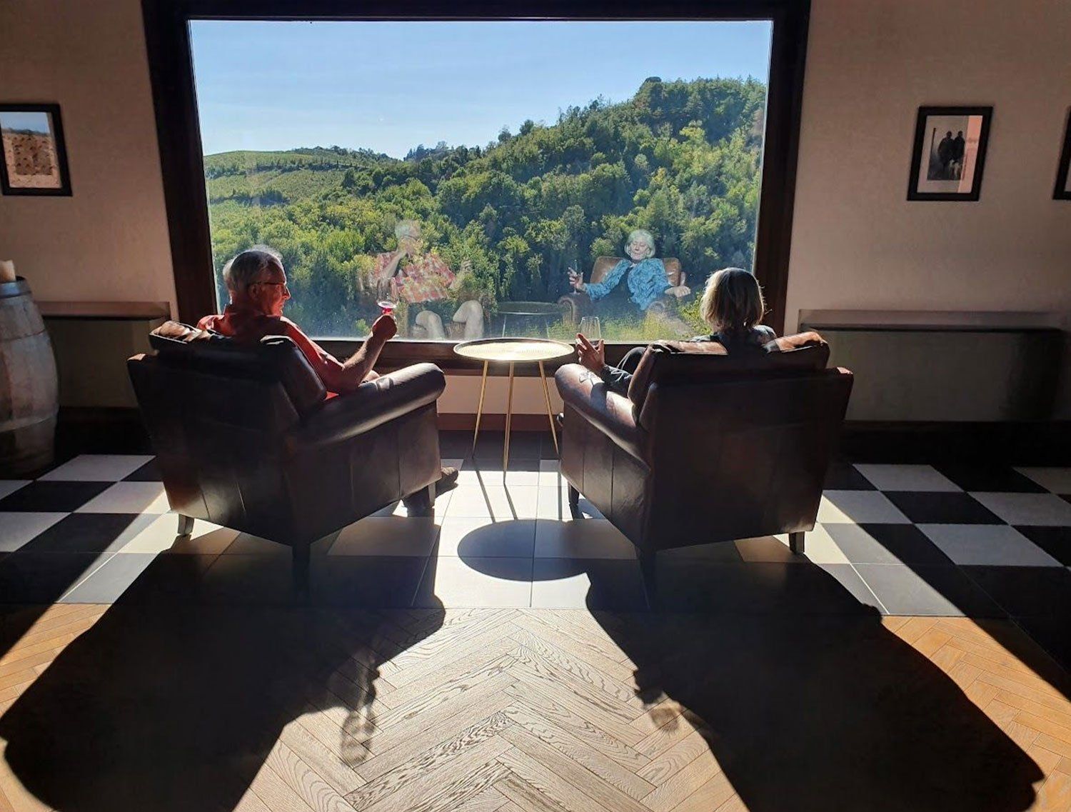 A cozy lounge with a large window reflecting a couple outside.