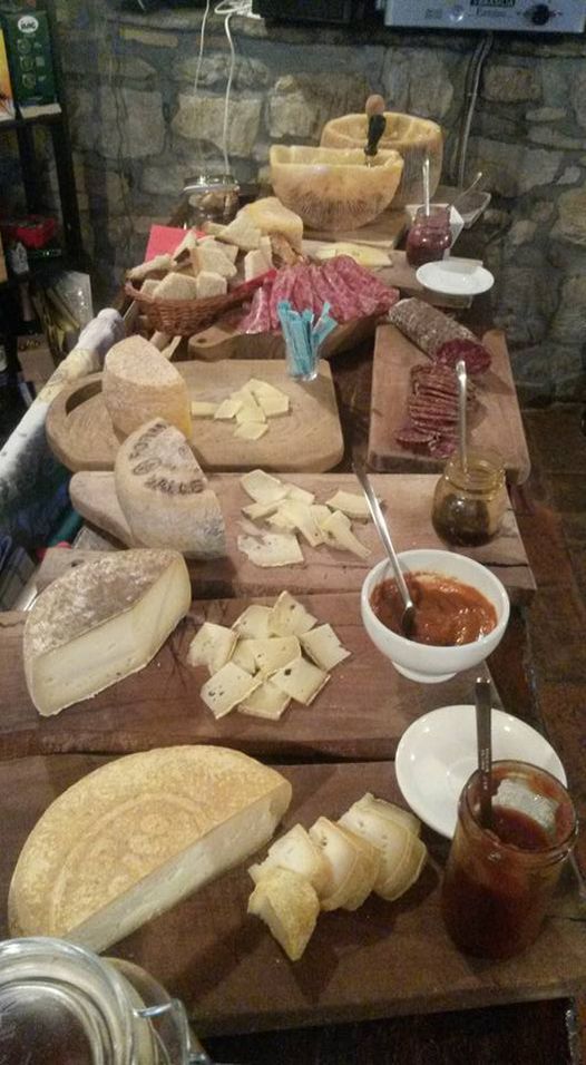 A rustic charcuterie spread with cheeses, cured meats, bread, and preserves on wooden boards.